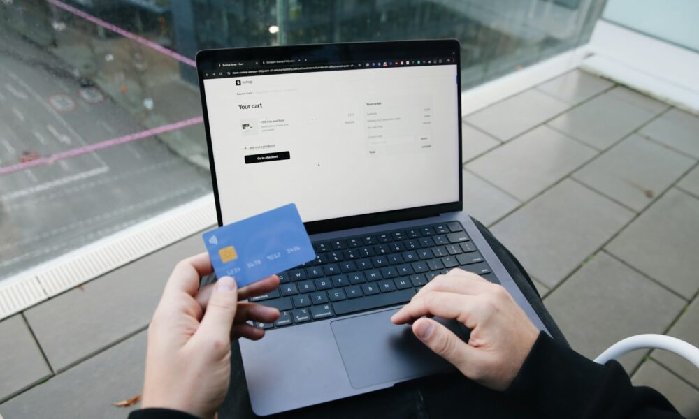 Ruce s platební kartou nad notebookem při nákupu na internetu