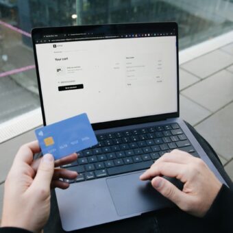 Ruce s platební kartou nad notebookem při nákupu na internetu