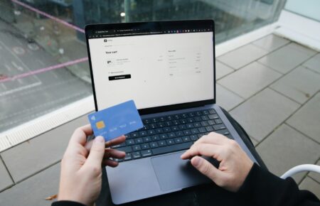 Ruce s platební kartou nad notebookem při nákupu na internetu