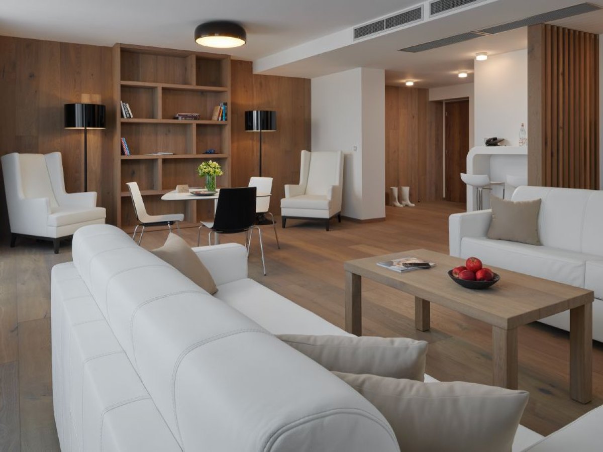 Prostorné apartmá hotelu Passage s bílou sedačkou a dřevěnými obklady