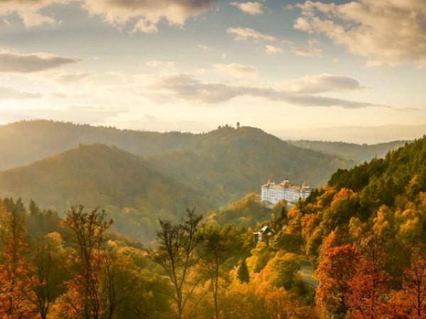 Hotel Imperial nad zalesněnými kopci Karlových Varů při západu slunce