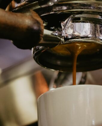 Espresso stéká z pákového kávovaru do bílého šálku