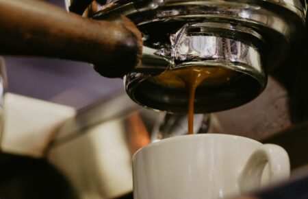 Espresso stéká z pákového kávovaru do bílého šálku