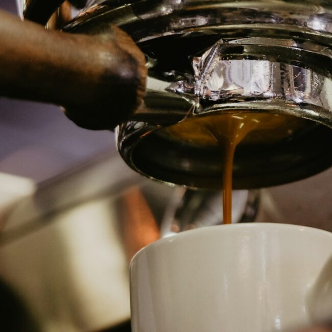 Espresso stéká z pákového kávovaru do bílého šálku