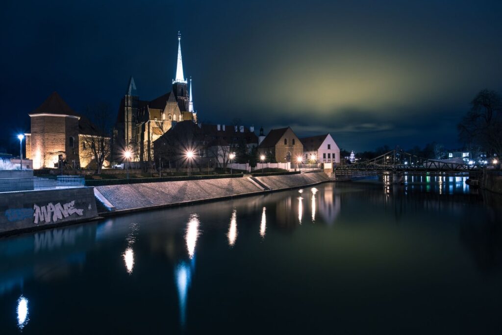 Ostrów Tumski we Wrocławiu nocą, odbity w Odrze