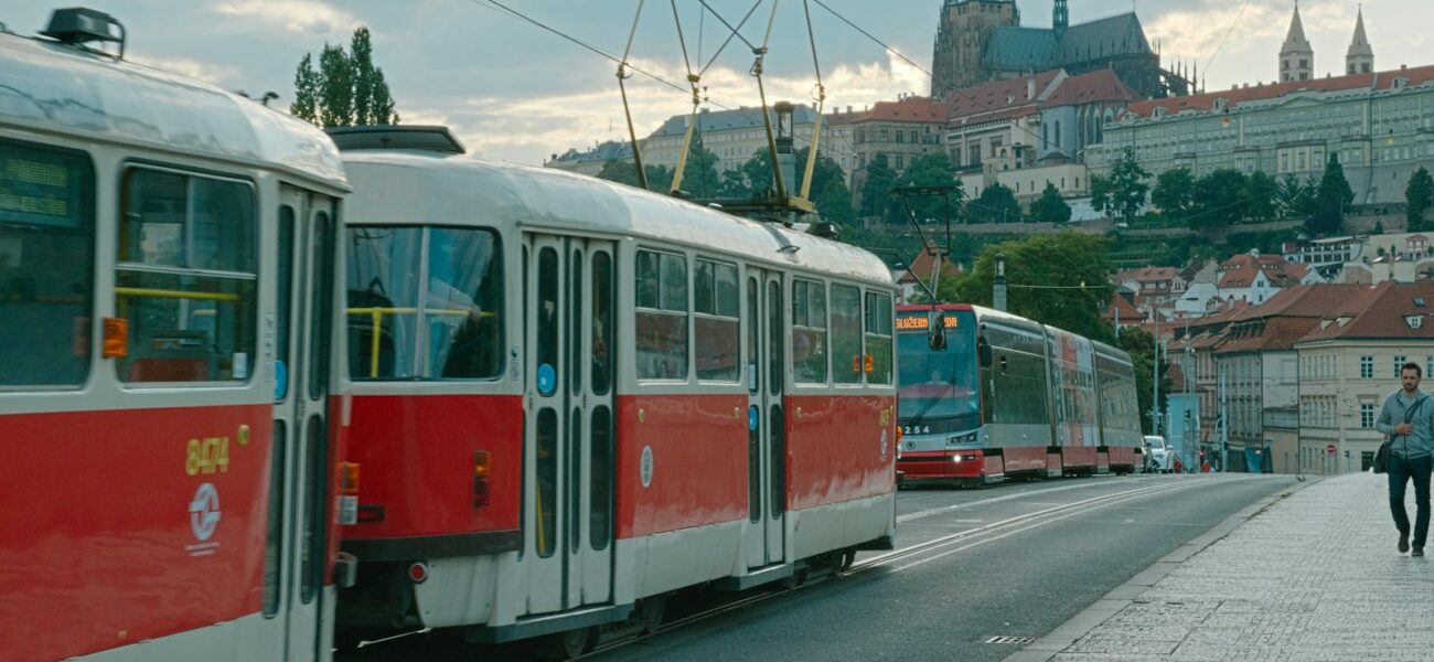 Červená pražská tramvaj na nábřeží s Pražským hradem v pozadí