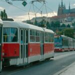 Červená pražská tramvaj na nábřeží s Pražským hradem v pozadí
