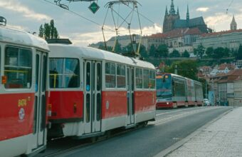 Červená pražská tramvaj na nábřeží s Pražským hradem v pozadí