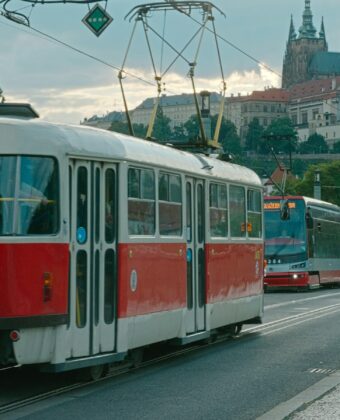 Červená pražská tramvaj na nábřeží s Pražským hradem v pozadí