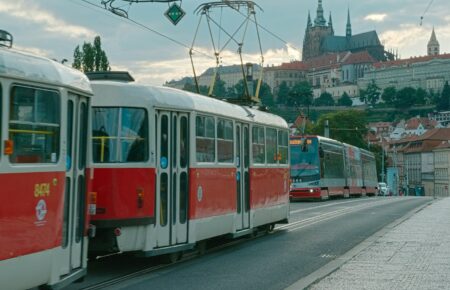 Červená pražská tramvaj na nábřeží s Pražským hradem v pozadí