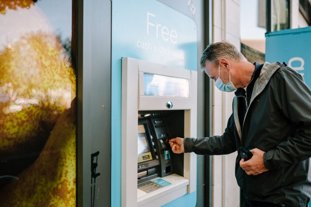 Mężczyzna wypłacający gotówkę z bankomatu
