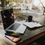 Laptop, notes i kawa na drewnianym biurku przy oknie