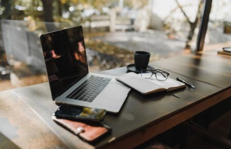 Laptop, notes i kawa na drewnianym biurku przy oknie