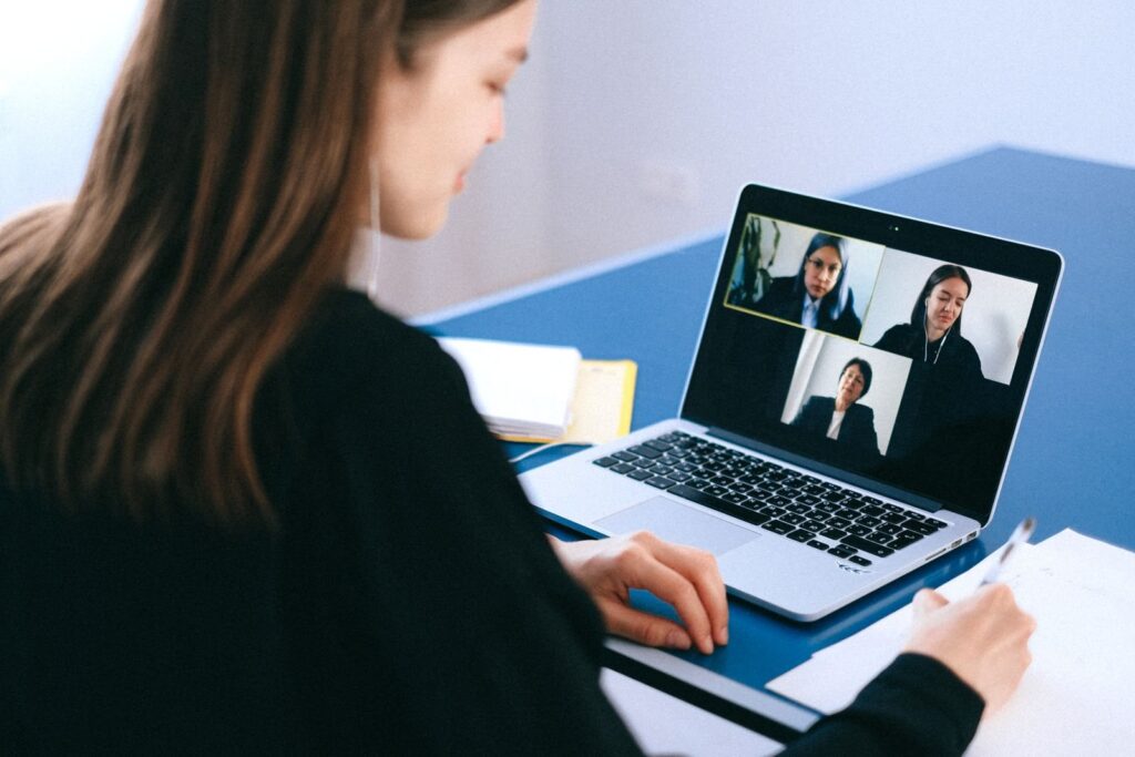 Kobieta podczas wideokonferencji na laptopie robiąca notatki