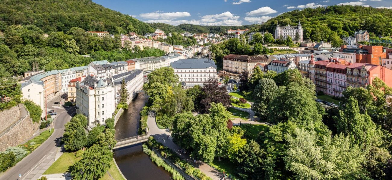Letecký pohled na Karlovy Vary s řekou Teplou a lázeňskými domy v zeleni