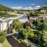Letecký pohled na Karlovy Vary s řekou Teplou a lázeňskými domy v zeleni