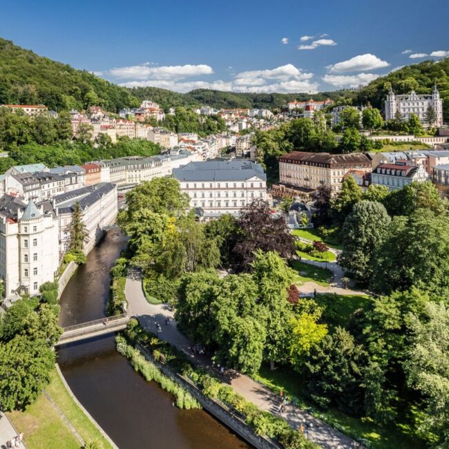 Letecký pohled na Karlovy Vary s řekou Teplou a lázeňskými domy v zeleni
