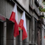 Biało-czerwone flagi na fasadzie kamienicy