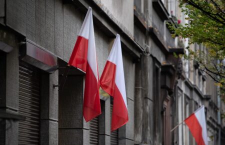 Biało-czerwone flagi na fasadzie kamienicy