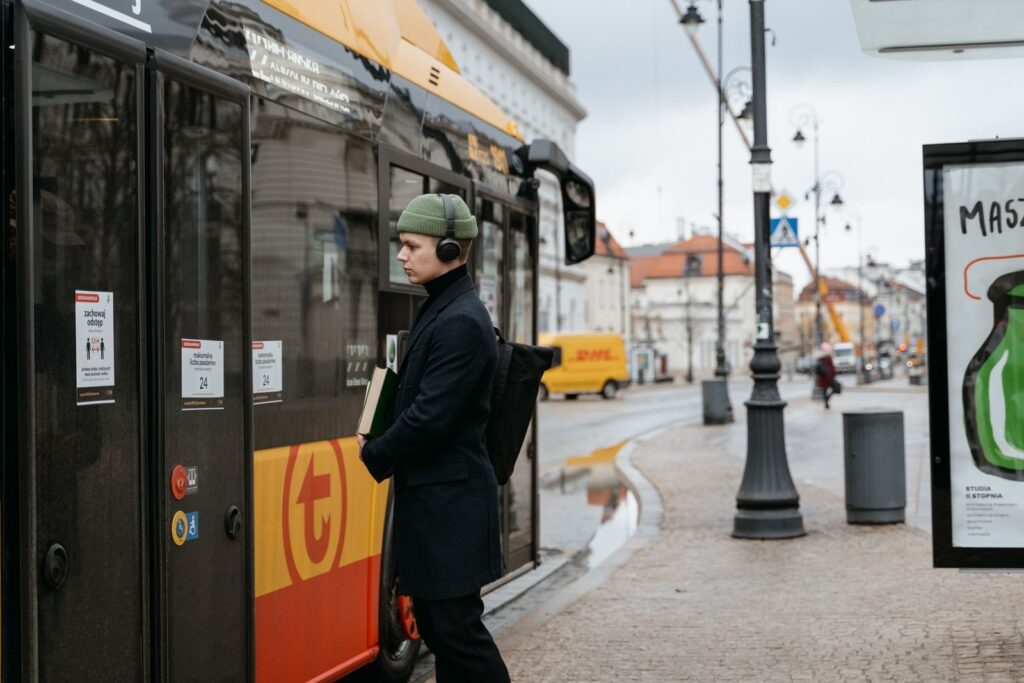 Mężczyzna w czapce i słuchawkach czekający na przystanku autobusowym