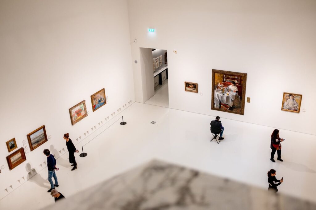 Zwiedzający oglądają obrazy w galerii muzealnej
